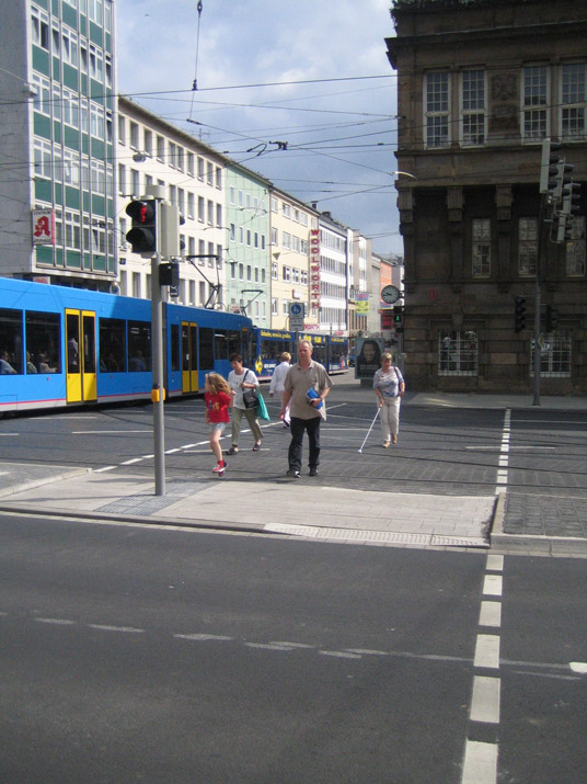 Ampelgeregelte Kreuzungsüberquerung mit Verkehrsinseln und Straßenbahnschienen